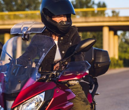 Vrouw met helm op een motor.